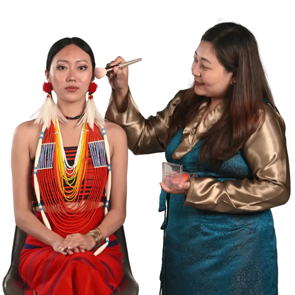 Beautician applying makeup for a client in traditional Naga attire